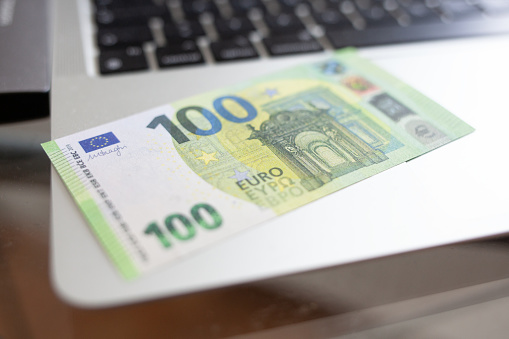 €100 banknote lies on the laptop as a symbol for earning money on the Internet