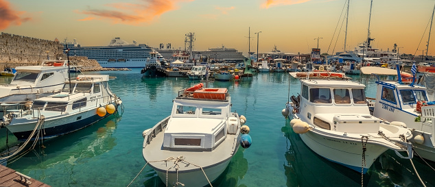 Rhodes: Yachts, boats and historic medieval walls of the Old Town dating from the Italian era, along the seafront promenade in picturesque port Mandraki marina.