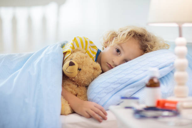 Sick little boy with asthma medicine. Ill child. Sick little boy with asthma medicine. Ill child lying in bed. Unwell kid with chamber inhaler for cough treatment. Flu season. Bedroom or hospital room for young patient. Healthcare and medication. only boys stock pictures, royalty-free photos & images