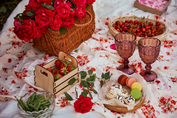 istock Romantic aesthetic pink picnic with tablecloth marshmallows, macaroons, strawberries, glasses of wine among pink roses in the park. Romantic dinner. Selective focus 1409503488