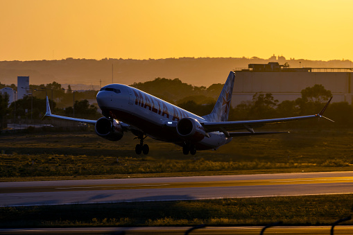 Luqa, Malta - July 13, 2022: Malta Air Boeing 737-8 MAX 200 (REG: 9H-VUA) taking off from runway 13 with the sun setting down behind.
