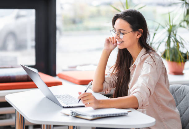 istock Female office worker or freelancer using laptop computer having video call in modern office or coworking. Young Successful woman working remotely sitting at the workplace 1409506105
