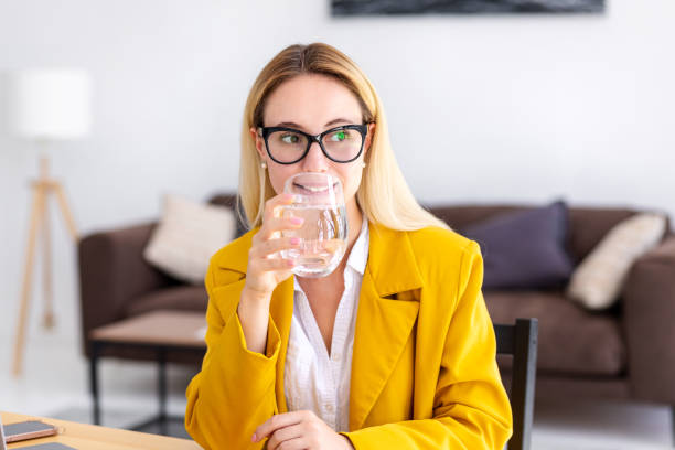 Healthy lifestyle concept. Young business woman drinking clean water sitting workplace in modern office. Recuperation concept stock photo