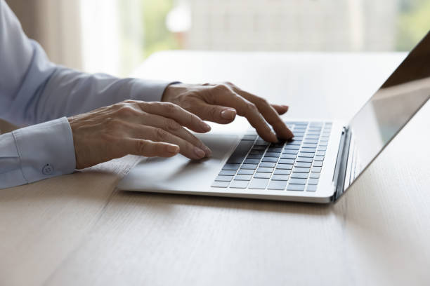 istock Close up view older female hands typing on laptop keyboard 1409509240