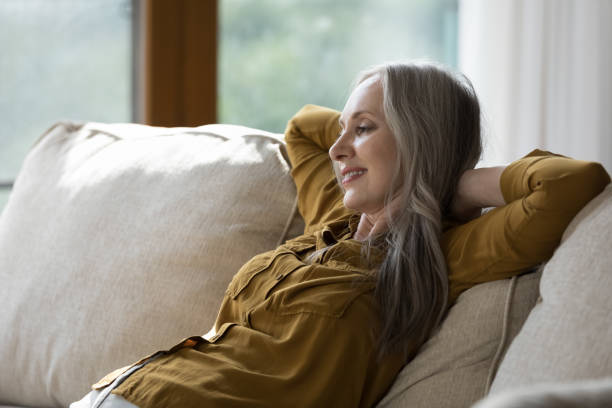 istock Beautiful mature woman put hands behind head relaxing on sofa 1409509275