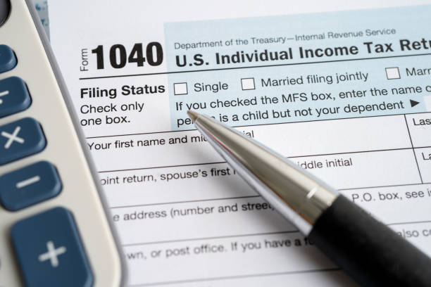 米国アメリカ国旗とドル紙幣、米国個人所得が記載された納税申告書フォーム1040。 - 税金 ストックフォトと画像