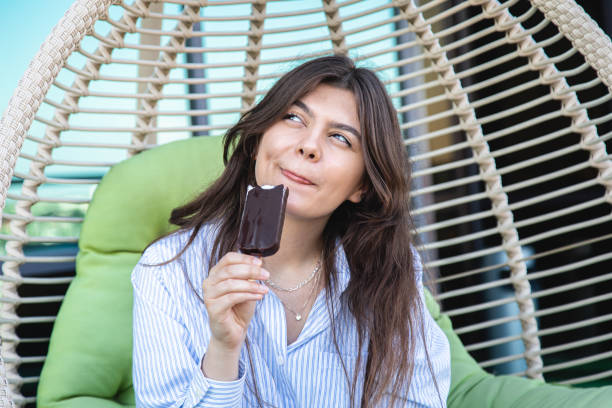istock Happy young woman with chocolate ice cream in a hammock. 1409512285