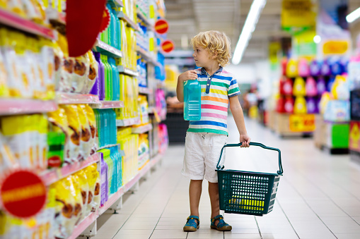 Child in supermarket buying fruit and juice. Kid grocery shopping. Little boy with cart choosing fresh vegetables in local store.