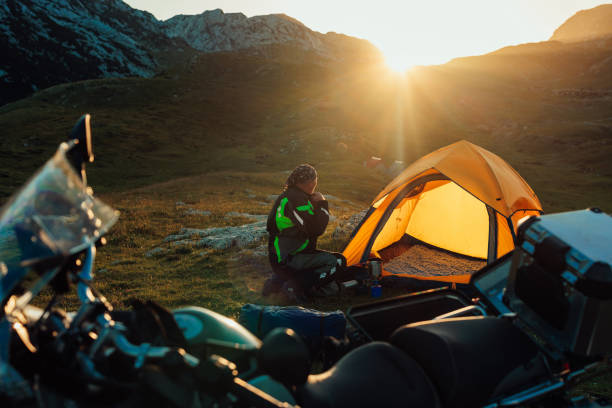istock Motorcyclist in a campground beside his tent 1409519210