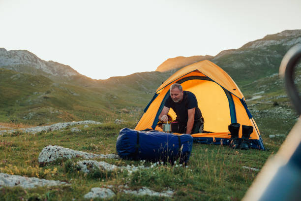 istock Motorcyclist sitting in tent, preparing food 1409519244