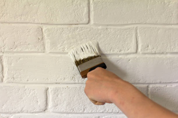 istock Painting a white brick wall in a fresh white color. 1409519749