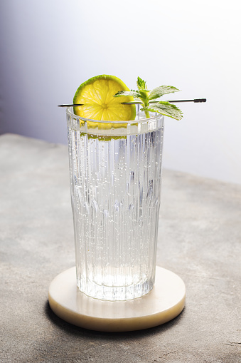 carbonated mineral water with lime and mint in the glass on gray background
