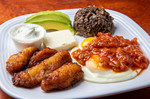 Salvadorian Breakfast (desayuno salvadoreno) fried plantain (platano maduro) , queso fresco, rice, sliced avocado, and fried eggs