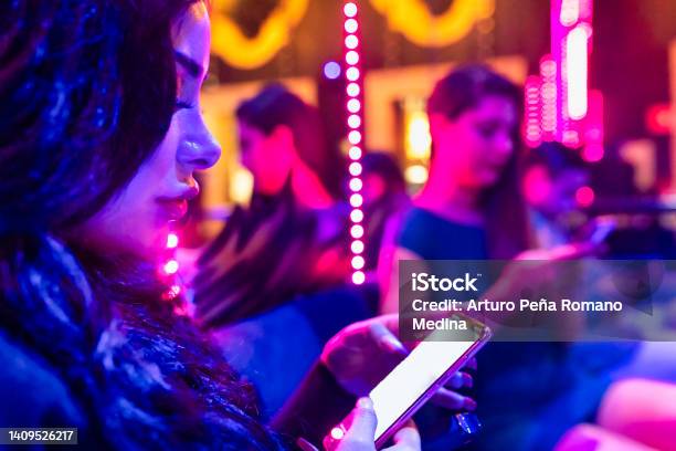 Girl In A Nightclub Using Cell Phone Stock Photo - Download Image Now - Night, Magenta, One Person
