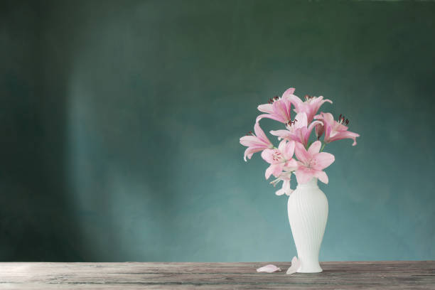 istock pink lily in white vase on blue background 1409527661