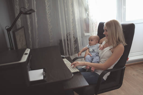 istock Mom with baby on hands works behind computer 1409529343