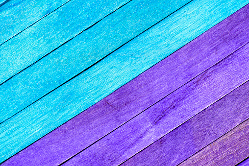 Bright two-tone background from wooden textured planks. Wooden boards painted in blue and purple are arranged diagonally. Painted textured wooden background with natural stucture.