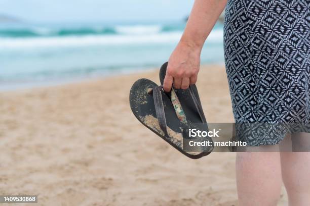 Closeup Of A Woman In A Geometric Patterned Dress Holding Sandals As She Walks Towards The Water At The Beach Stock Photo - Download Image Now