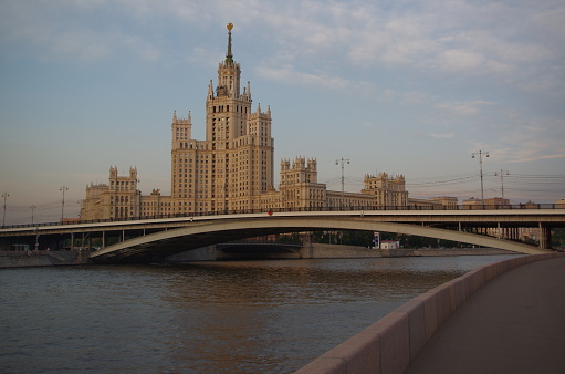 the moscow river, the big ustinsk bridge and the stalin skyscraper on the kotelnicheskaya embankment in moscow against the backdrop of the evening blue sky