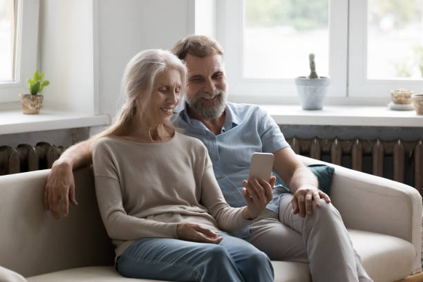 istock Happy elder married couple using mobile phone at home 1409531337