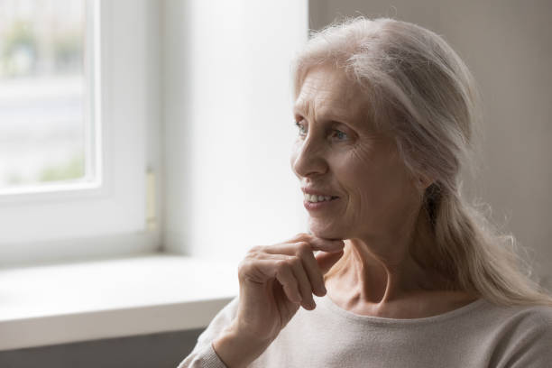 istock Happy thoughtful senior 70s lady looking away, touching chin 1409531345