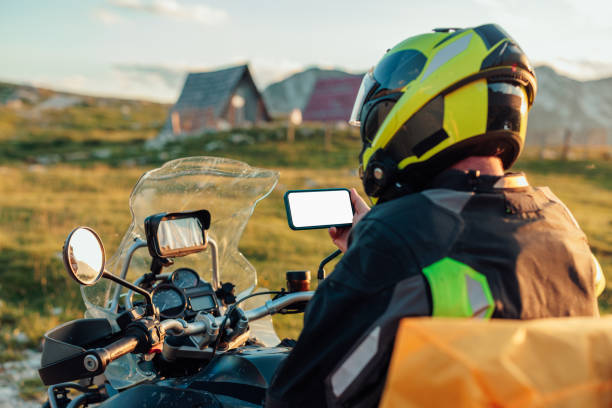 istock A biker holding a mobile phone in his hand. Mountain countryside background 1409533438