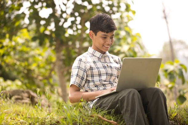 istock Happy teenage boy using laptop while sitting outdoors on rural ground 1409533680