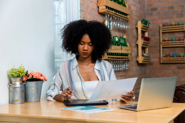 Business woman using digital table and working on laptop computer in modern home office.