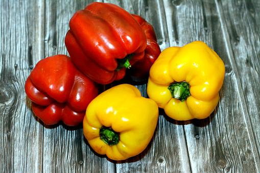Fresh organic colorful red and yellow bell peppers and paprika isolated on wooden background, selective focus of healthy organic food for good health and weight loss using vegetables diet