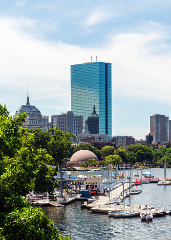 Boston, Massachusetts, USA - July 15, 2022: View of the Community Boating organization sailing marina on the Charles River Esplanade between the Hatch Shell and the Longfellow Bridge. The Back Bay skyline, including the John Hancock Tower, is in the background.