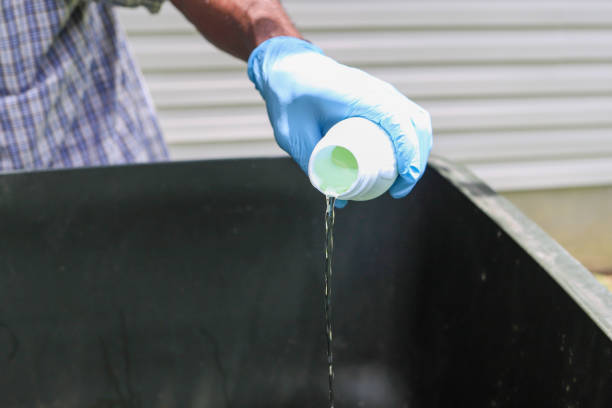 A black African-American man pouring bleach in a dirty garage can stock photo