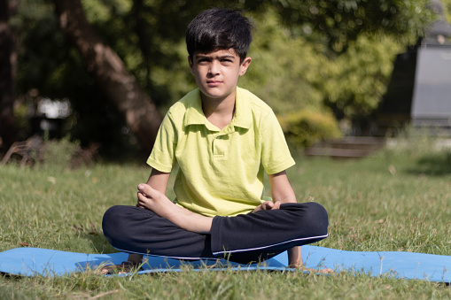 Young little Kid Practicing Yoga Asana Outdoors in the park in Morning, healthy lifestyle concept, Kids yoga