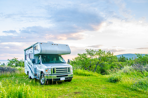 Motorhome parked on grass during sunset in summer time
