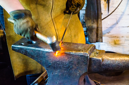 Close-up of blacksmith manually forging the molten metal in the workshop