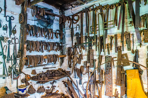 Old and rusty blacksmith tools hanging on wall workshop
