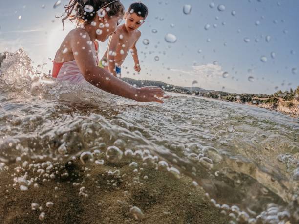 Brother with his little sister playing together in the sea on vacation.
