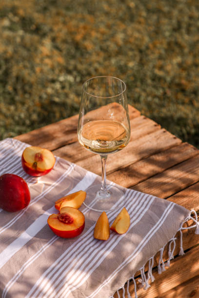 White Wine glass in summer garden with peaches on wooden crate picnic White Wine glass in summer garden with peaches on wooden crate picnic food styling stock pictures, royalty-free photos & images