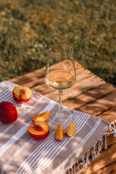 white wine glass in summer garden with peaches on wooden crate picnic - food styling imagens e fotografias de stock