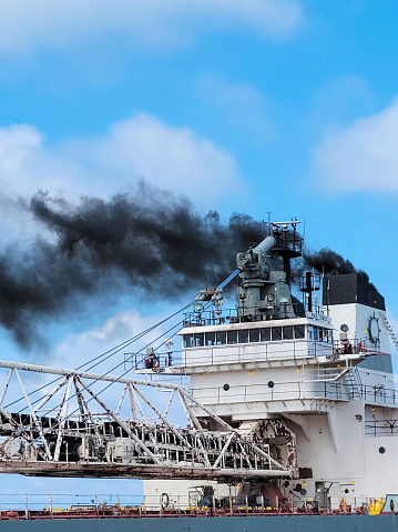 Great Lakes freighter with a smokestack and black smoke exhaust