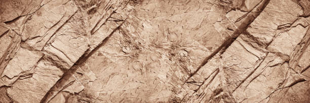 istock Light brown rock texture. Rough mountain surface with cracks. Close-up. Sand color stone background with space for design. 1409544626