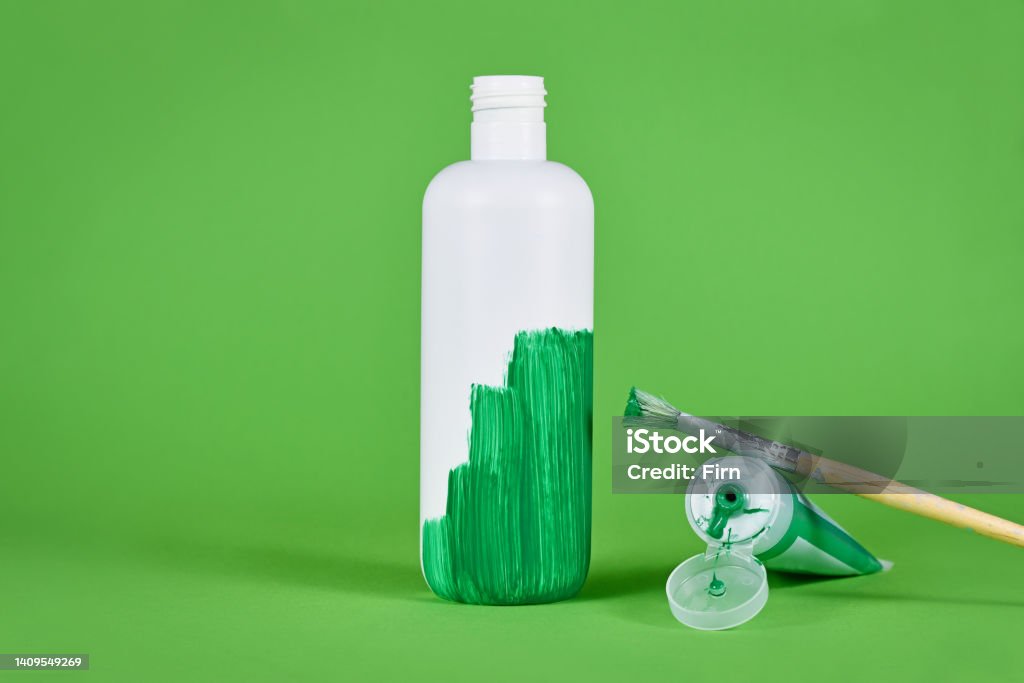 Greenwashing concept Greenwashing concept with white plastic bottle being painted green Greenwashing Stock Photo