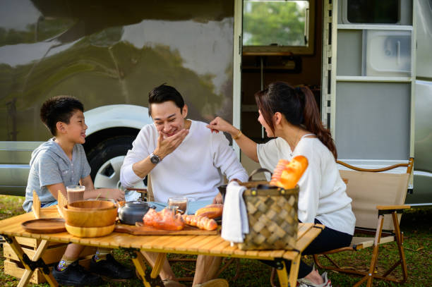 istock Happy Asian parents and their kid enjoy their breakfast while spending a spring day on camping. - Camper van travel series 1409551225