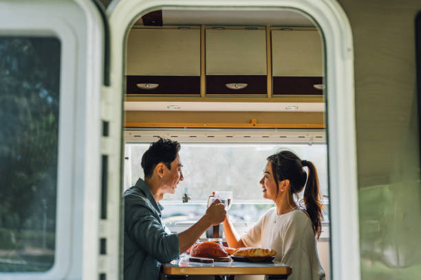 Lovely Asian Chinese couple enjoy breakfast with their camper van - Camper van travel series Lovely Asian Chinese couple enjoy their breakfast and coffee at the camper rv travel stock pictures, royalty-free photos & images