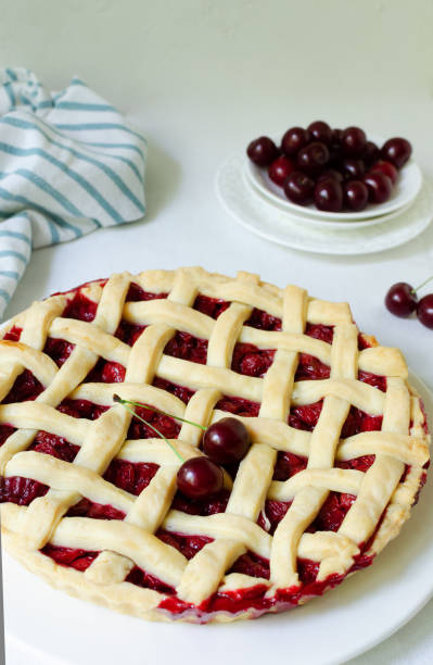 istock Homemade cherry pie on a large white plate with ribs on a white tablecloth on the table. The concept of traditional baking. Seasonal pie. Vertical orientation. 1409552510