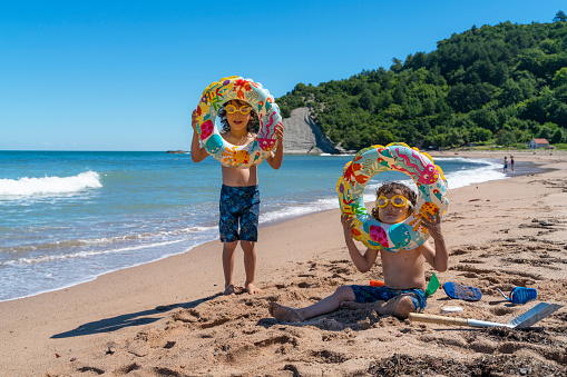 Children spending their summer vacation by the sea. Having fun on the beach on a sunny and hot summer day. \nShot with a full frame camera.