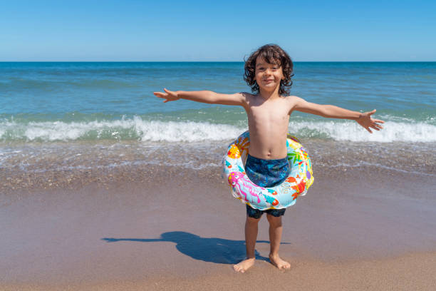 Children spending their summer vacation by the sea. Having fun on the beach on a sunny and hot summer day. Shot with a full frame camera.
