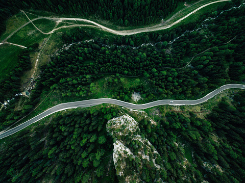 Aerial view of a winding road in the forest. S-shape road in Dolomites mountains, Italy.