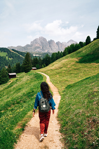 A woman is walking on a path in the Dolomites, Trentino Alto Adige, Italy. She's enjoying her vacation in the nature.