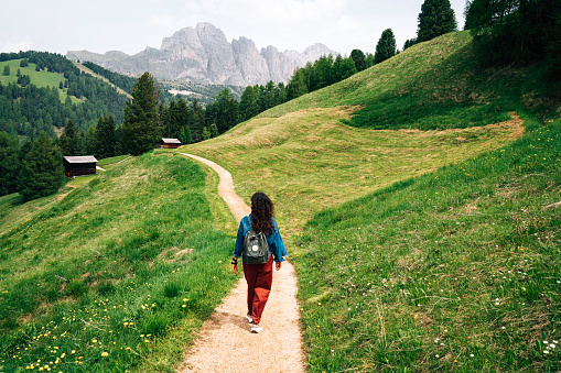 A woman is walking on a path in the Dolomites, Trentino Alto Adige, Italy. She's enjoying her vacation in the nature.