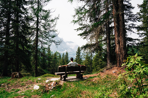 An empty bench in the Dolomites, Italy. Mountain range in the background.